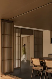 A modern dining room with wooden sliding doors and a wooden dining table and chairs.