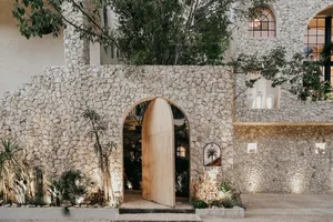 A modern residential entryway featuring a stone wall and wooden gate.