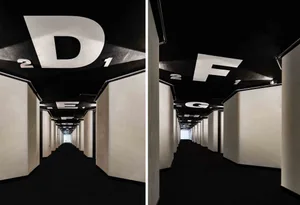 A modern industrial corridor interior design featuring a metal ceiling layout and large white letters on the ceiling.