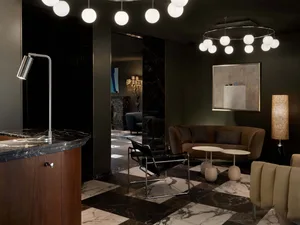 A modern living room with a marble floor, a beige sofa, and a black chair.