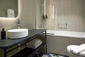 Modern, minimalist bathroom with grey tiled walls, a walk-in shower, and a large vanity sink.