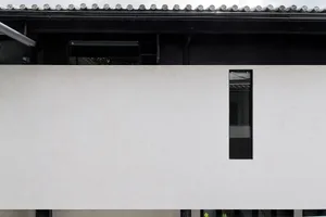 A modern residential building with a concrete exterior, minimalist design, and a unique geometric window.