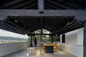 A modern roof terrace with wooden beams and a view of distant hills and buildings.