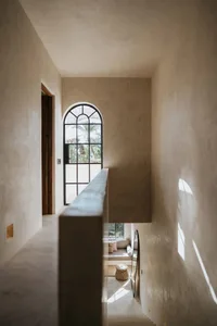 Modern residential stairwell with concrete and plaster walls featuring a lighting panel.