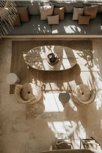 A living room with wicker furniture and woven baskets, featuring a round wooden table and a large sofa adorned with cushions.