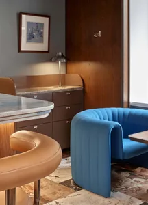Marble bar counter with a blue sofa and a brown leather stool in a restaurant setting.