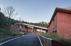 Modern brick building exterior with a sloping roof and stone pathways