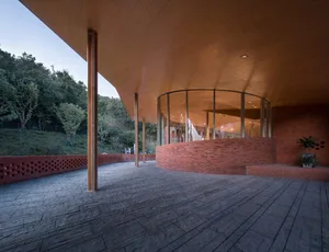Modern building facade featuring red brick and extensive glass.