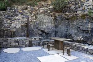 Industrial aesthetic with stone walls, wooden table, and benches.