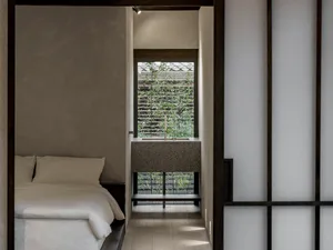 A minimalist bedroom with a solid stone bathroom sink counter, white bedding, and white walls.
