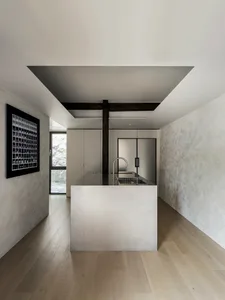 Modern kitchen with minimalist design featuring concrete countertops and stainless steel appliances.