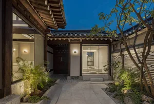 A minimalist residential exterior featuring wooden beams and a traditional tile roof at dusk.