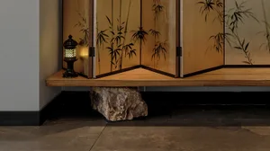 A minimalist storage unit with bamboo decorations on a wooden floor.
