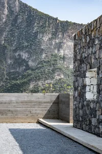 A modern exterior building constructed with stone materials, featuring a mountainous backdrop.