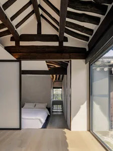 A minimalist bedroom with wood flooring and white walls.