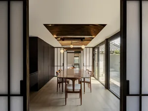 A modern minimalist dining room with wooden furniture and a cozy ambiance.