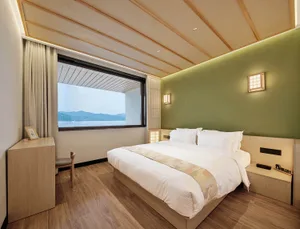 Modern residential bedroom with minimalist design, white bedding, and wood flooring.
