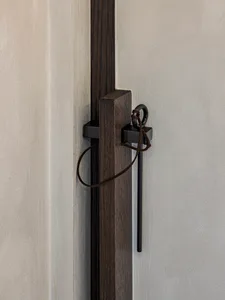 A modern wooden door handle mounted on a wooden post