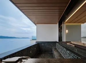 A view from a balcony featuring a glass window overlooking a serene body of water.