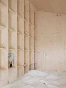 A minimalist bedroom with wooden walls and shelves.