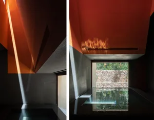 A minimalist swimming pool with concrete walls and a view of nature through a window.