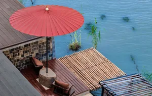 A minimalist terrace with a wooden platform overlooking water.