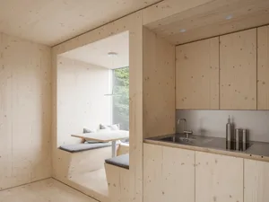 Modern minimalist kitchen with a wooden interior and a built-in seating area.