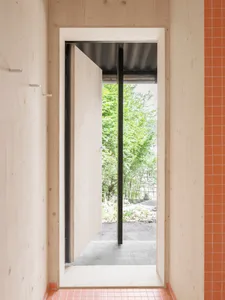 Modern minimalist entryway with wooden walls and a partially open door