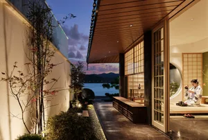 A modern living room with a glass wall overlooking a serene water view.