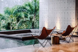 Modern lounge area with leather chairs and concrete walls.