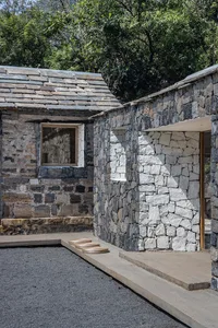 A modern residential exterior with stone walls and a wooden door and window.