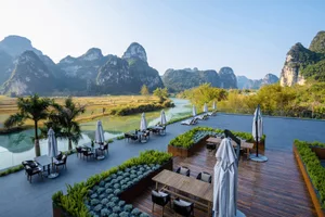 Outdoor seating area with tables and umbrellas overlooking scenic mountains