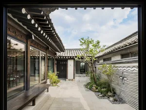 Traditional Korean yard with wooden structures, glass walls, and stone paths.