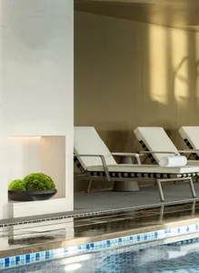 An elegant modern spa area featuring tiled poolside loungers and a wooden wall.