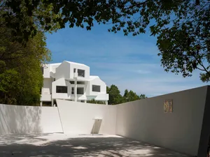 Modern white minimalist house exterior with white walls and flat surfaces.