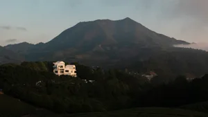 A serene mountain landscape with a prominent white building in the foreground, surrounded by lush greenery and rolling hills.