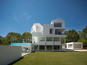 A minimalist modern house with a concrete structure and large windows.