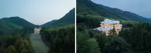 A modern house with a glass exterior nestled among lush green mountains.