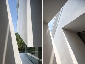 Modern minimalist interior with white concrete walls and ceiling, featuring geometric architectural elements.