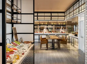 Modern restaurant interior with chefs preparing food behind a buffet counter.