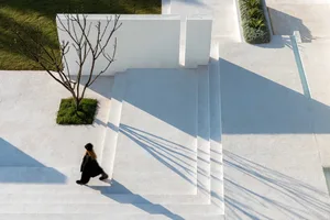 A modern exterior space with white concrete steps and surrounding concrete patio.
