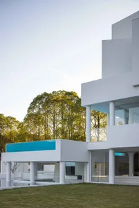 A modern house with large glass walls and white columns