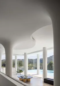A modern minimalist pool house featuring glass, concrete, and marble materials.