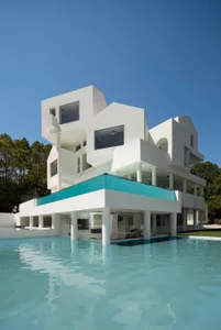 Contemporary residential building with minimalist design, primarily constructed from white concrete, glass, and steel.