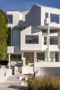 Modern white house with concrete exterior and large glass windows.