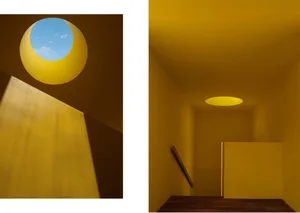 An interior design image featuring minimalist architecture with yellow walls and a circular window.