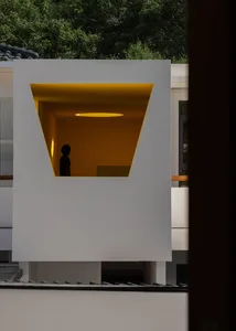 Modern, minimalist interior with a white, geometric space and a glowing yellow light source.