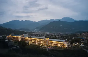 A resort with concrete, glass, and metal structures amidst a mountainous landscape.