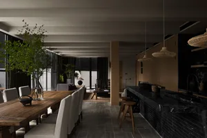 Modern dining area featuring a wooden table with upholstered chairs and a black marble kitchen counter.