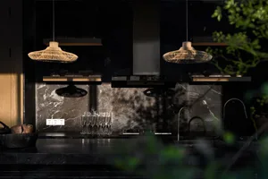 Modern kitchen with marble countertops and pendant lights hanging above.